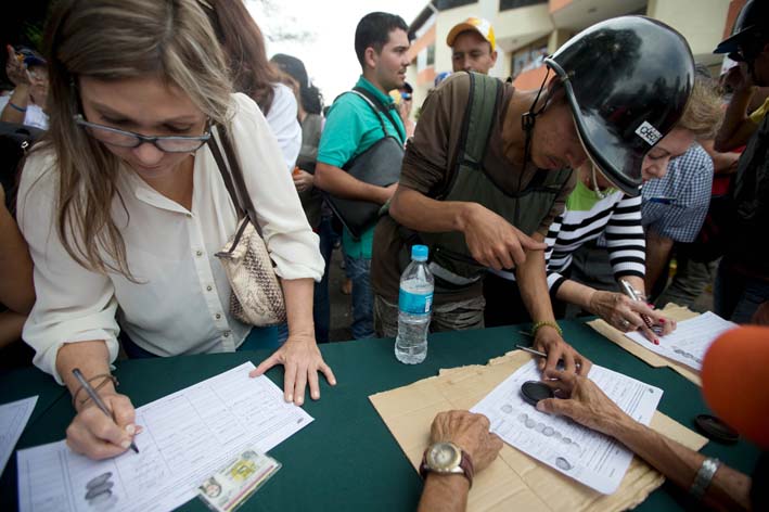 Las personas firman la lista organizada por la oposición, para iniciar un referendo revocatorio contra el presidente de Venezuela