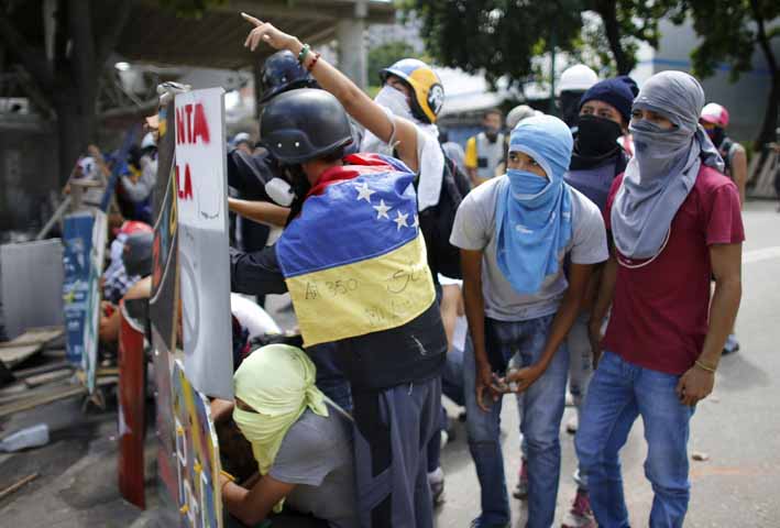 Un manifestante presiona a los oficiales de la Guardia Nacional Bolivariana en el primer día de una huelga general de 48 horas en protesta por los planes del gobierno para reescribir la constitución.