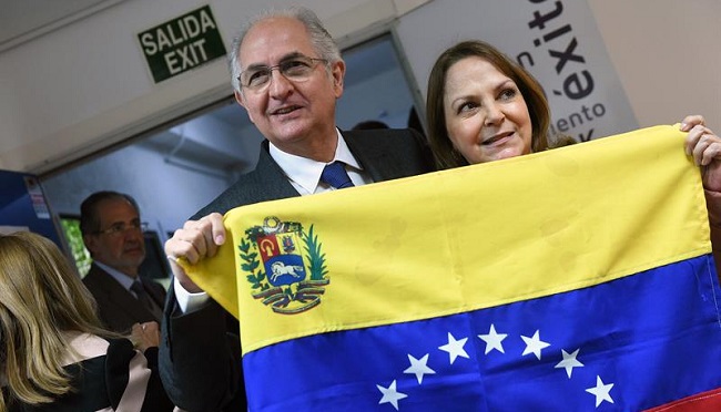 El alcalde metropolitano de Caracas y opositor venezolano, Antonio Ledezma, posa junto a su mujer Mitzy Capriles, tras una bandera de Venezuela, antes de la rueda de prensa que ha ofrecido en Madrid. EFE