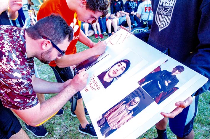 Varios estudiantes firman un poster con fotografías de Joaquín Oliver, una de las 17 víctimas mortales de la matanza perpetrada el miércoles por Nikolas Cruz en la escuela secundaria Marjory Stoneman Douglas.