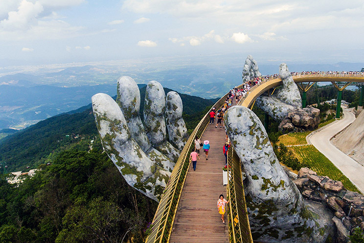 Varios turistas cruzan el nuevo puente Cau Vang (Puente Dorado), construido sobre la estructura gigante de unas manos, sobre las colinas Ba Na, cerca de la localidad Da Nang (Vietnam).