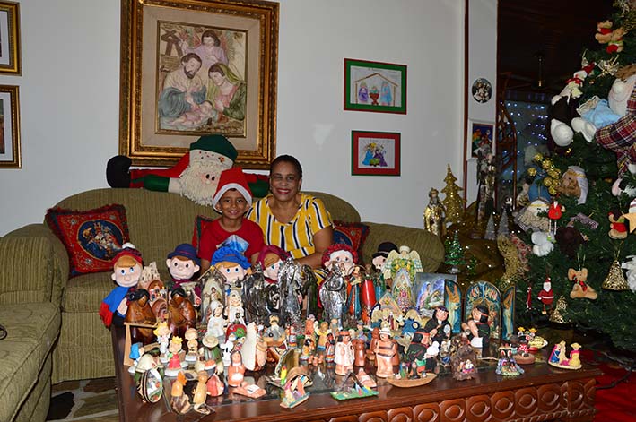 Nelly López Conde junto a su nieto, Isaac Guerra Conde, rodeados de algunos de los pesebres ubicados en la sala de la casa.