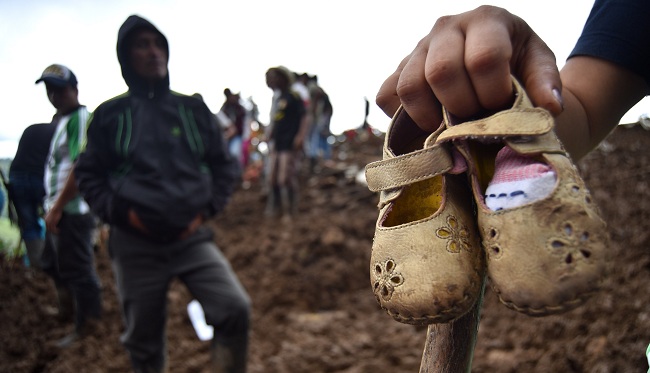 Una persona muestra unos zapatos de niña, tras un deslizamiento de tierra, en la vereda Portachuelo, en el municipio de Rosas, Cauca. Las autoridades colombianas reanudaron este lunes las operaciones de búsqueda y rescate de más de una decena de desaparecidos por el deslizamiento de tierra causado por las fuertes lluvias. Foto: EFE