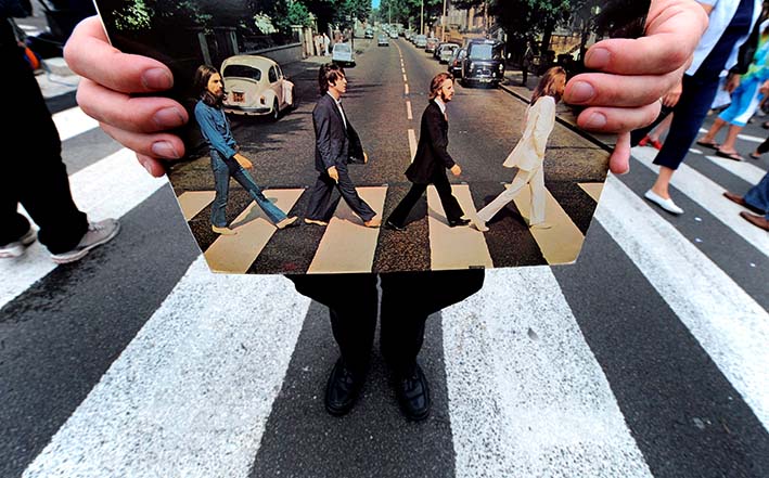 El guía turístico Richard Porter muestra una copia del álbum Abbey Road del grupo británico The Beatles en Londres (Reino Unido), sobre el mismo paso de cebra. Foto EFE/Andy Rain