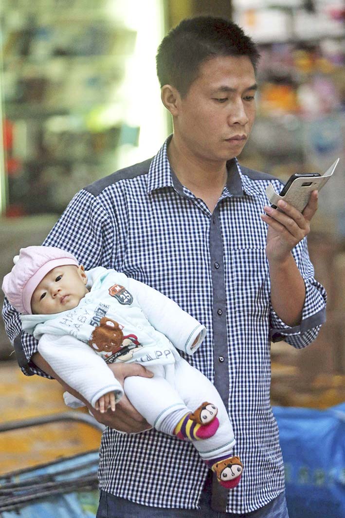 Un hombre observa en la pantalla de su teléfono móvil una aplicación de bebés. EFE/Wu Hong