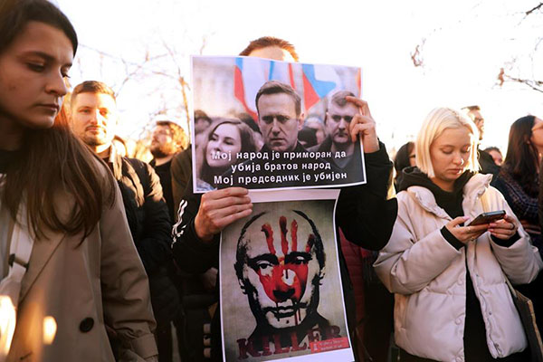 Un hombre sostiene pancartas que representan a Alexei Navalny con un texto que dice “Mi pueblo se ve obligado a matar al pueblo de mi hermano, mi presidente ha sido asesinado”.