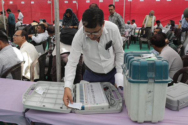 Los funcionarios electorales indios con las máquinas de votación electrónica selladas y las máquinas expendedoras esperan antes de su viaje a los colegios electorales para la primera fase de las elecciones.