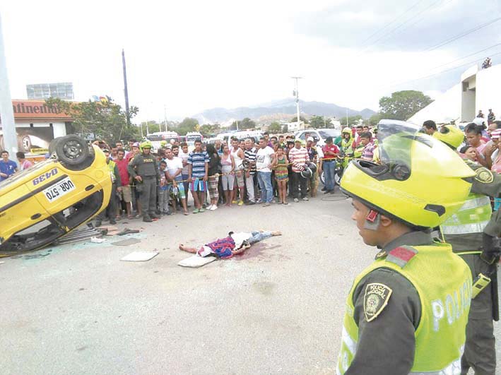 El cadáver del joven motociclista junto al taxi que lo arrolló.