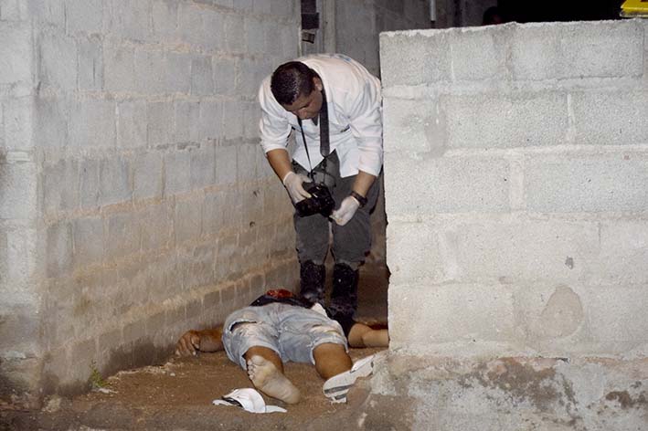 Personal de criminalística haciendo labores de levantamiento del cadáver.