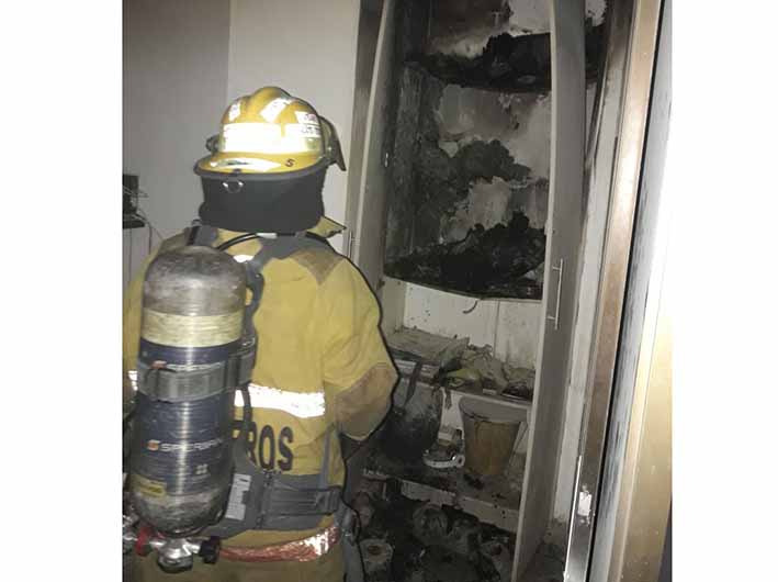 Momento en que bomberos atienden un incendio estructural, en el barrio el Pando, donde se encontró un closet prendido en llamas.