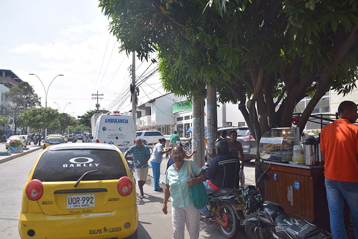 Negocios informales y motocicletas obstaculizan el paso, haciendo que los transeúntes caminen por la calle.