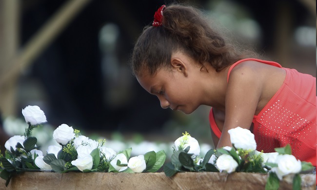 Una niña decora un bote este lunes para recibir los restos de las víctimas de la masacre ocurrida en 2002, en Bojayá, Colombia.