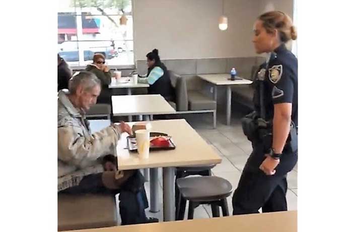 Policía de Estados Unidos saca a mendigo de un restaurante de comida rápida.