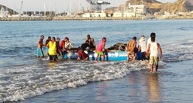 Pescadores llegan a la orilla de Los Cocos para sacar sus redes de la canoa.