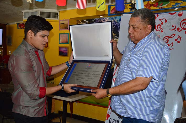 Estrada Latorre recibiendo el reconocimiento a su padre por parte de Armando Romero, director de Sayco.
