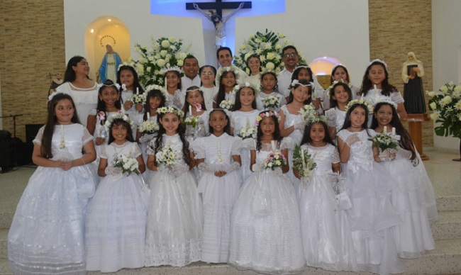 El presbítero Gustavo Acevedo, acompañado del grupo de niñas que recibieron por primera vez el Cuerpo y la Sangre de Cristo en la solemne eucaristía en la capilla del Instituto La Milagrosa.