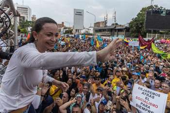 La líder opositora María Corina Machado saluda a sus simpatizantes en un acto político en una avenida en Maracaibo.