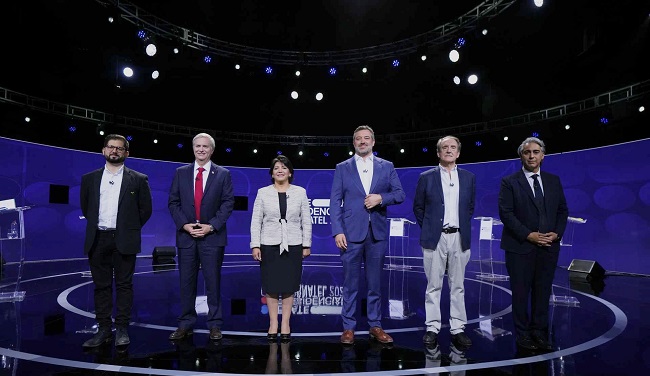 Ellos son los candidatos presidenciales: por el Frente Amplio, Gabriel Boric; por el Partido Republicano, José Antonio Kast; por el Partido Demócrata Cristiano, Yasna Provoste; por Chile Vamos, Sebastián Sichel; por Unión Patriótica, Eduardo Artés, y por el Partido Progresista, Marco Enríquez-Ominami. La fotografía fue tomada durante uno de los últimos debates presidenciales, sin embargo, el candidato independiente Franco Parisi no estuvo en el país para la fecha. 