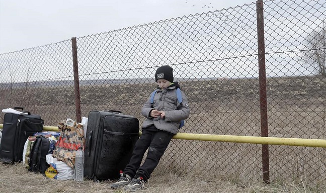 Un niño refugiado ucraniano espera a su madre cerca del equipaje de su familia después de pasar el cruce fronterizo rumano-ucraniano en Siret, en el norte de Rumania.