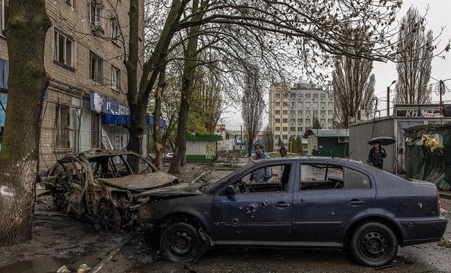 Las personas se paran junto a los automóviles destruidos en el área residencial que fue alcanzada por el bombardeo de la artillería rusa.