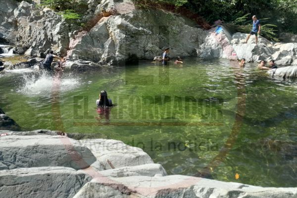 Una mujer registra con su teléfono una fotografía de la piscina natural más profunda de Quebrada Valencia mientras un grupo de personas disfruta del balneario y de las cascadas.  Fotos: Rony Barrera. Derechos Reservados/ELINFORMADOR