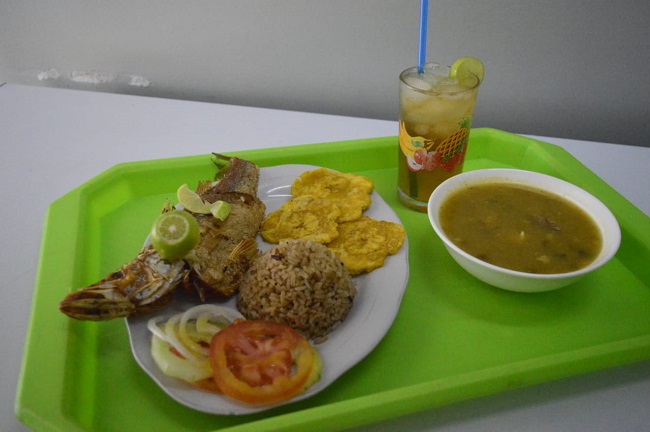 Lebranche frito acompañado con patacones de plátano verde, arroz con coco, ensalada, sopa de pescado y agua de panela.