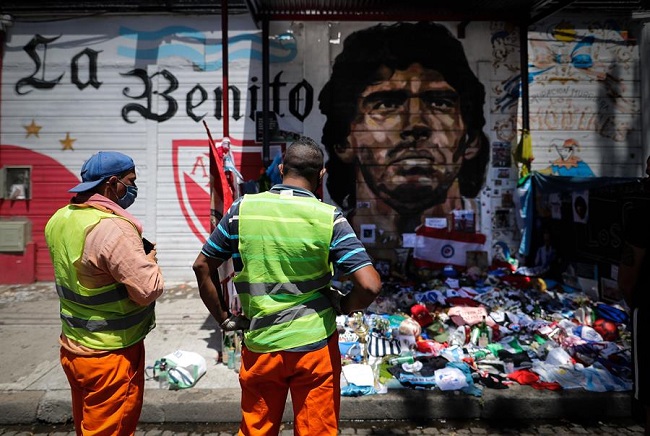 Personas dejan ofrendas en un mural de Diego Maradona convertido en santuario en el Estadio de Argentinos Juniors.