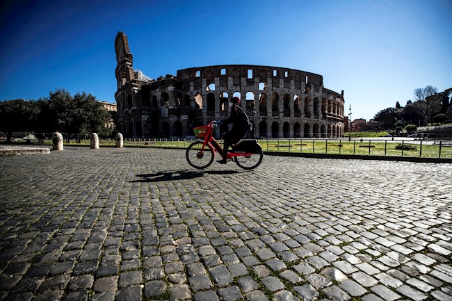 Una persona monta en bicicleta ante el Coliso romano durante el nuevo confinamiento, en Roma, hoy 15 de marzo.EFE