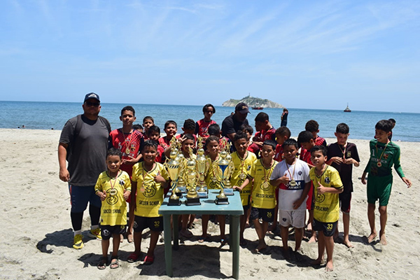 Renso Modera entrega medallas a jóvenes jugadores en la clausura del Torneo Comunitario de Fútbol Playa, celebrado en la Playa de los Cocos durante la Fiesta del Mar en Santa Marta.