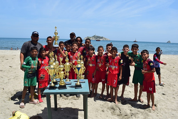 : Un grupo de niños celebra su victoria en el Torneo Comunitario de Fútbol Playa, un evento que subrayó la importancia de la deportividad y la recreación en el desarrollo juvenil.