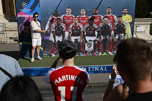 Un seguidor del Arsenal posa junto a una figura de cartón del equipo durante el festival de la UEFA Champions League en la Plaza de los Héroes de Budapest. Foto EFE/EPA/ANNA SZILAGYI