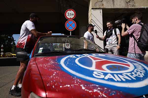 Aficionados del PSG hablan con miembros de la prensa, a las afueras del ‘Puskás Arena’ en Budapest.  Foto EFE/EPA/ANNA SZILAGYI