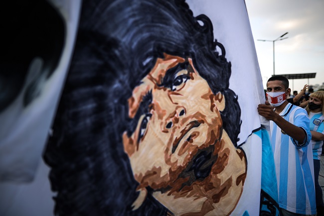 Un aficionado sostiene una bandera con la imagen de Diego Armando Maradona el día de la muerte del astro argentino, en el Obelisco en Buenos Aires. Maradona, genio y figura, fue uno de los grandes personajes del siglo XX y XXI.