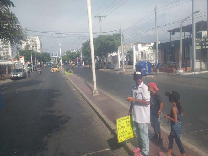 Los menores piden dinero en los semáforos de la ciudad mientras sus padres muestran carteleras con mensajes solicitando ayuda. 