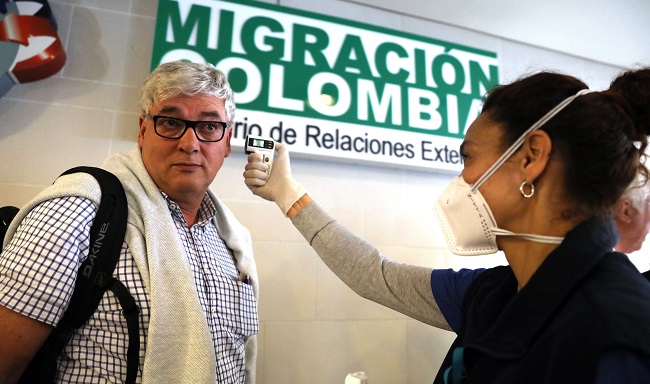 Funcionarios toman la temperatura de los ciudadanos que llegan este jueves al aeropuerto internacional El Dorado, como parte de las medidas de prevención para despachar y recibir pasajeros, en Bogotá. Foto EFE.