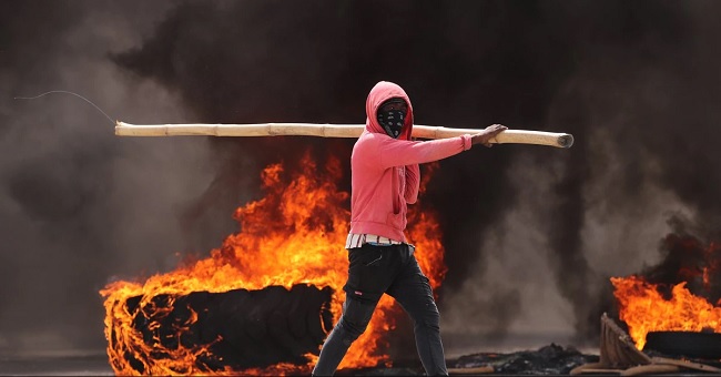 Un hombre camina junto a un neumático gigante en llamas durante una jornada de protestas en Haití, en una fotografía de archivo. EFE