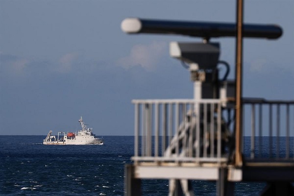 Una embarcación marina maniobra más allá de una torre de radar mientras navega lejos del lugar donde el ejército chino creía que realizaba un simulacro de fuego.