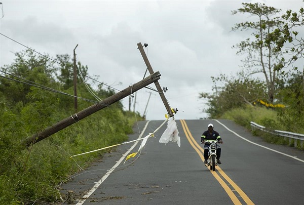Un motorista pasa junto a un poste de alumbrado público que fue derribado durante el paso del huracán Fiona.