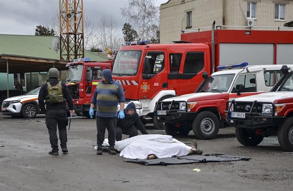 Los hombres se preparan para mover el cuerpo de un rescatista ucraniano que murió en un bombardeo de una estación de bomberos en Kherson.