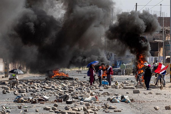 Personas caminan entre barricadas durante las manifestaciones en la ciudad de Tacna, Perú.