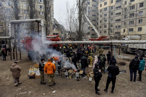 Los lugareños y los rescatistas reciben alimentos en el patio de un edificio residencial dañado en Dnipro, sureste de Ucrania.