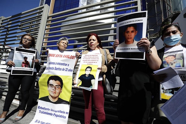 Varias personas participan en un plantón con fotografías y documentación sobre personas desaparecidas en la Fiscalía en San Salvador.
