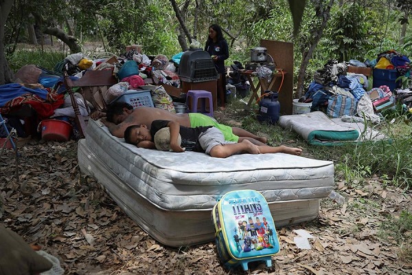 Habitantes descansan junto a sus pertenencias rescatadas de sus viviendas afectadas tras el desborde del río Chillón en Lima.