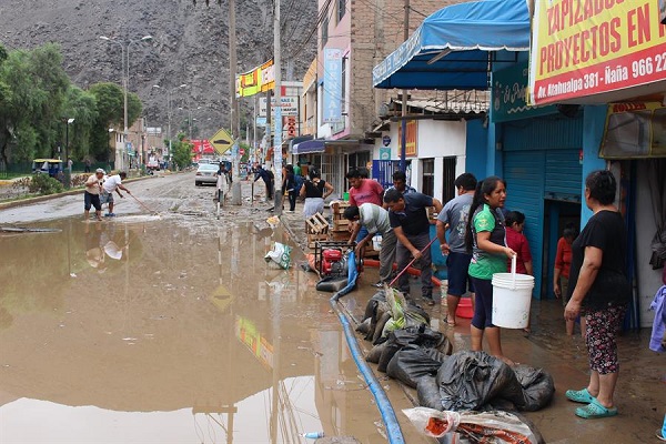 Residentes intentan sacar el agua de sus casas y locales inundados por el ciclón Yaku, en el distrito de Chaclacayo en Lima.