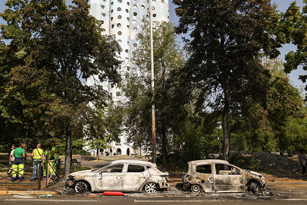 Un trabajador municipal limpia la calle junto a un coche incendiado en la avenida Pablo Picasso tras una noche de disturbios civiles, en Nanterre, cerca de París.