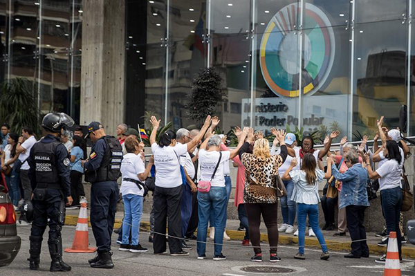 Varias personas rezan mientras participan en una protesta en la entrada del Ministerio de Educación en Caracas.