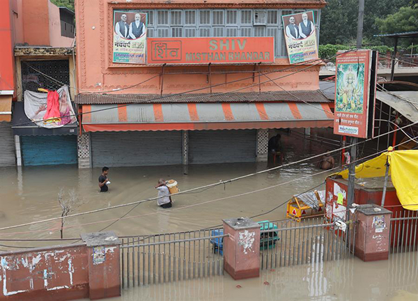 La gente camina por el mercado inundado de Yamuna Bazar después de que las aguas del río Yamuna sumergieron las carreteras en Nueva Delhi.