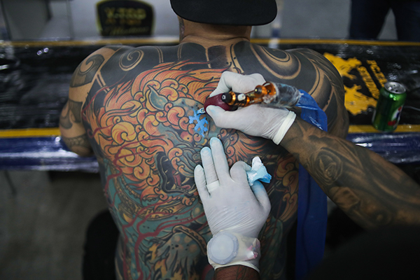 Un tatuador trabaja sobre la piel de un hombre. El 17 de julio se  celebra el Día Internacional del tatuaje. EFE/André Coelho