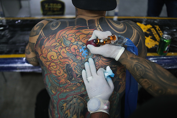 Un tatuador trabaja sobre la piel de un hombre. El 17 de julio se celebra el Día Internacional del tatuaje. EFE/André Coelho