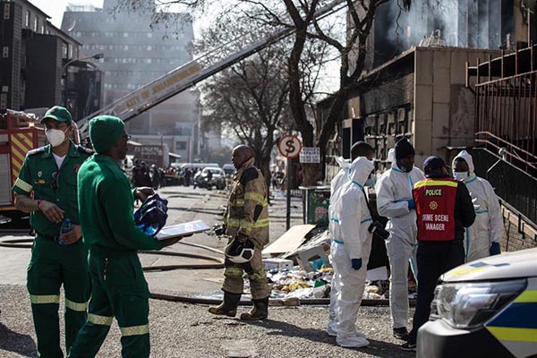 Bomberos, personal de emergencia y policía se reúnen en el lugar de un incendio que se produjo en un edificio de cinco plantas en el centro de la ciudad, en Johannesburgo.